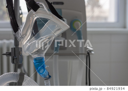 Non-invasive ventilation face mask, side view, on background medical ventilator in ICU in hospital. 84921934