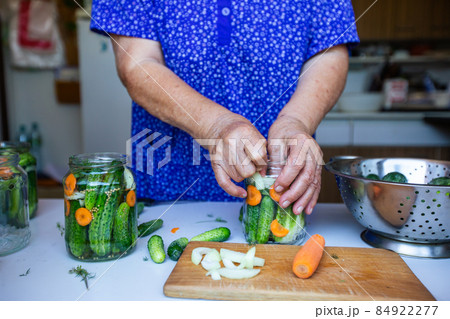 Process of canning a cucumber, senior woman canning fresh cucumbers with onion and carrots, homemade product, food concept Process of canning a cucumber, senior woman canning fresh cucumbers with onion and carrots, homemade product, food concept 84922277