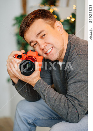 man with camera in red silicone case against background of Christmas decorations 84922853