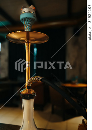 Gold hookah on table in lounge cafe. Gold hookah on table in lounge cafe. 84924108