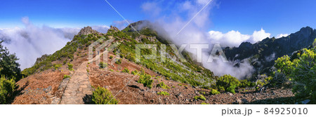 Hiking activity in Madeira island rocky mountains. Trail for Pico Ruivo highest point passing in the clouds Hiking activity in Madeira island rocky mountains. Trail for Pico Ruivo highest point passing in the clouds 84925010