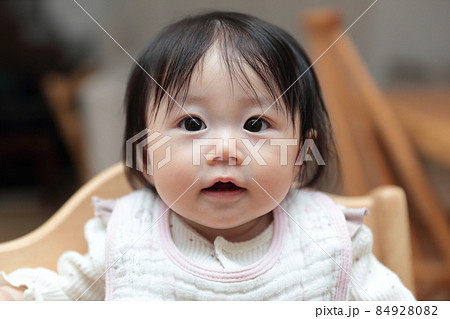 つかまり立ちをする生後半年の赤ちゃんの女の子の写真素材