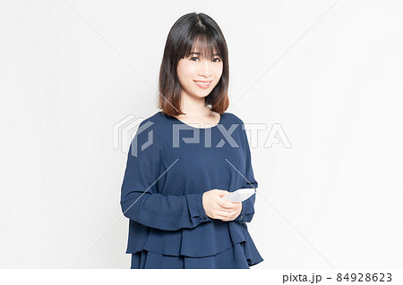 白い背景の前に立って、電話の子機を使う若い女性 84928623