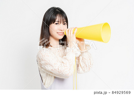 白い背景の前に立って応援するレースのブラウスを着た若い女性 白い背景の前に立って応援するレースのブラウスを着た若い女性 84929569