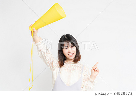 白い背景の前に立って応援するレースのブラウスを着た若い女性 白い背景の前に立って応援するレースのブラウスを着た若い女性 84929572