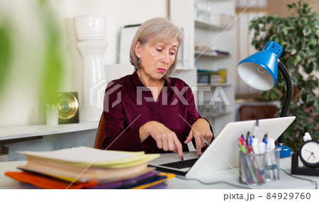 Upset frustrated elderly female entrepreneur sitting in office with laptop Upset frustrated elderly female entrepreneur sitting in office with laptop 84929760