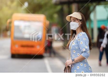 woman with medical mask to protect coronavirus(covid-19) while waiting bus at bus stop in city woman with medical mask to protect coronavirus(covid-19) while waiting bus at bus stop in city 84930202