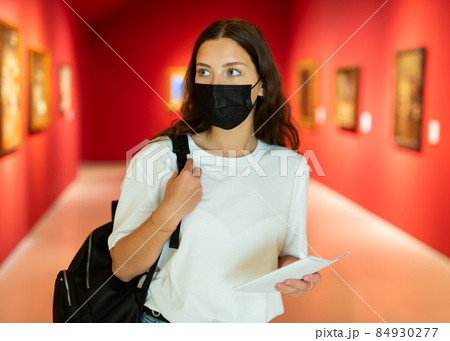 Young girl in a protective mask visits an exhibition of paintings in a museum Young girl in a protective mask visits an exhibition of paintings in a museum 84930277