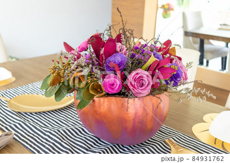 Floral arrangement of roses inside decorated pumpkin 84931762