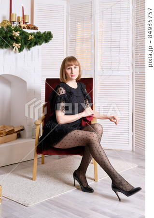Pretty woman sits in armchair in living room with chrictmas decor 84935757
