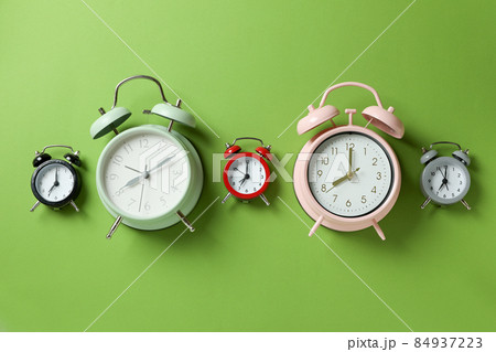 Different multicolor alarm clocks on green background 84937223
