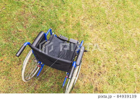 Empty wheelchair standing in hospital park waiting for patient services. Wheel chair for person with disability parked outdoor. Accessible for person with disability. Health care medical concept Empty wheelchair standing in hospital park waiting for patient services. Wheel chair for person with disability parked outdoor. Accessible for person with disability. Health care medical concept 84939139