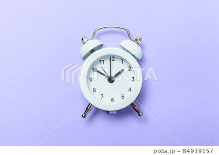 Vintage classic alarm clock colored in trendy color of year 2022 Very Peri background. Flat lay top view copy space. Inspired by using color 17-3938. Color of the year concept 84939157