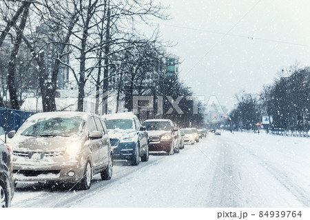 Scenic view traffic city jam at crossroad dirt snow covered slippery road drive slow moving cars stuck. Snowfall danger blizzard bad winter weather. Urban cold foggy day snowstrom town background 84939764