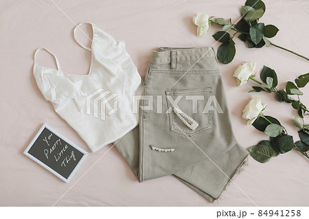 Women jeans, sandals, lingerie and flowers top view. Women's stylish spring summer outfit. Trendy clothes. Flat lay. 84941258