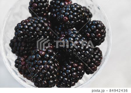 Fresh blackberries in a patterned glass bowl on gray background 84942436