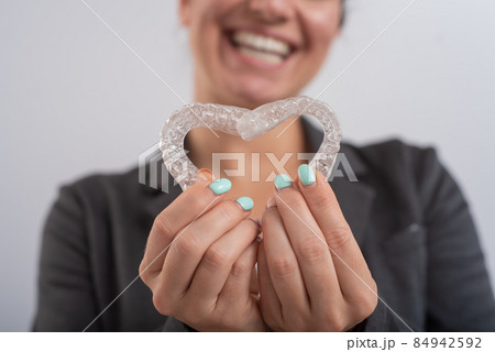 Caucasian woman holding two transparent heart-shaped aligners Caucasian woman holding two transparent heart-shaped aligners 84942592