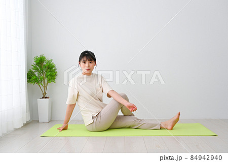 屋内のマットの上でストレッチ体操をする若い女性 屋内のマットの上でストレッチ体操をする若い女性 84942940