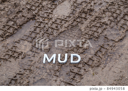 the word mud laid with silver metal letters on wet dirt surface 84943058