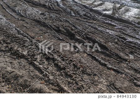 close-up full frame view of wet muddy dirt road at evening sun light close-up full frame view of wet muddy dirt road at evening sun light 84943130