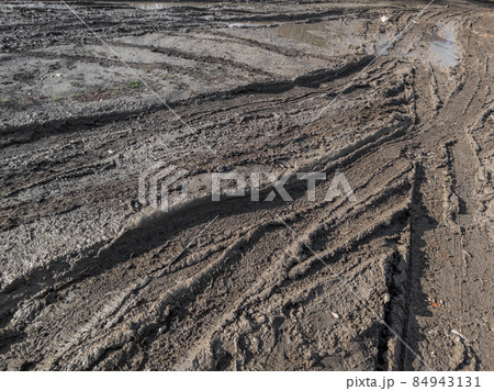 close-up full frame view of wet muddy dirt road at evening sun light close-up full frame view of wet muddy dirt road at evening sun light 84943131