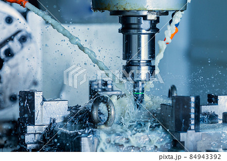 vertical cnc steel milling process with external water coolant streams, splashes and a lot of metal chips, high contrast 84943392