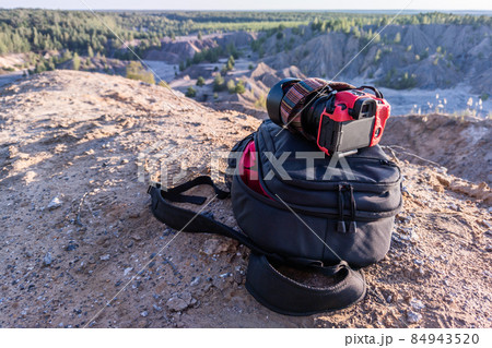 professional camera and photo backpack on top of the hill at summer daytime professional camera and photo backpack on top of the hill at summer daytime 84943520