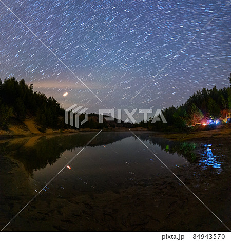 small lake under stars at night with short rails and camping at summer 84943570