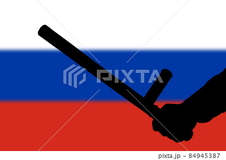 hand with police tonfa rubber stick silhouette and blurry russian flag in the background 84945387