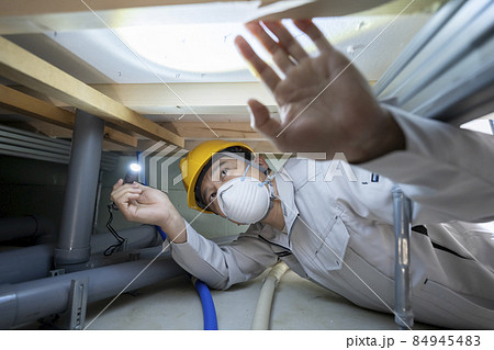 住宅の床下を点検する作業服の男性 84945483