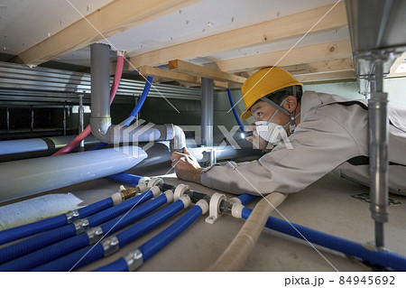住宅の床下の配管を点検する作業服の男性 住宅の床下の配管を点検する作業服の男性 84945692