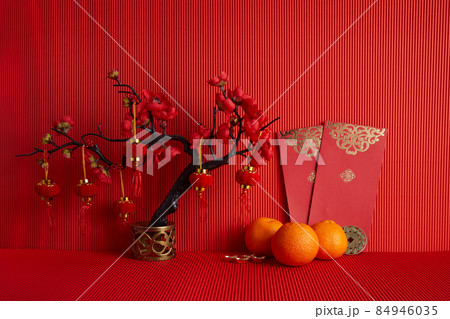 Chinese new year festival decorations. Orange, leaf, red packet, plum blossom on red background. 84946035