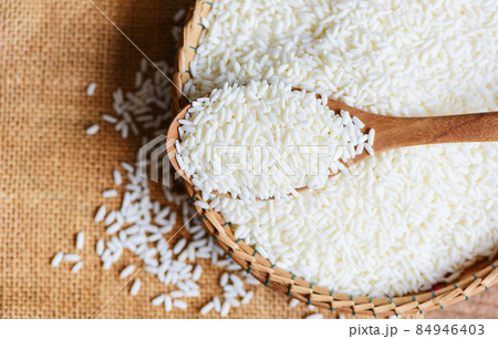 Jasmine white rice on wooden spoon on the basket in the the sack, harvest rice and food grains cooking concept Jasmine white rice on wooden spoon on the basket in the the sack, harvest rice and food grains cooking concept 84946403