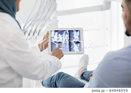 Oral Surgery. Female Dentist In Hijab Demonstrating Teeth Xray On Digital Tablet Oral Surgery. Female Dentist In Hijab Demonstrating Teeth Xray On Digital Tablet 84948459