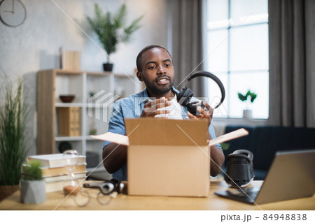 Man sitting at the table at home unpacking box with headphones Man sitting at the table at home unpacking box with headphones 84948838