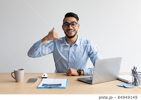 Portrait of smiling Arab man making call me gesture Portrait of smiling Arab man making call me gesture 84949149