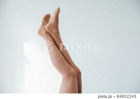 beautiful slender women's legs in tights stockings on a white background beautiful slender women's legs in tights stockings on a white background 84952245
