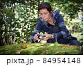 Girl taking pictures of nature in the forest on the big stone with moss 84954148