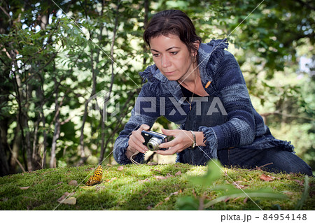 Girl taking pictures of nature in the forest on the big stone with moss 84954148