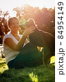 A happy teenage girl sits on a lawn and plays with a dog to hug him 84954149