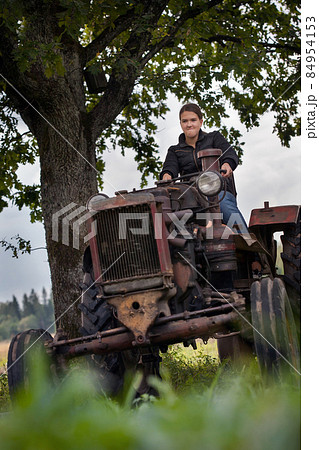 Young girl, old tractor and old oak 84954153