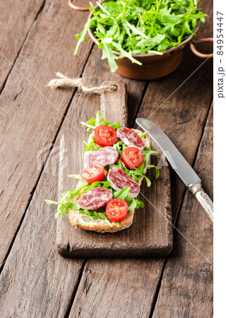 Tasty sandwich with arugula salad on wooden background 84954447