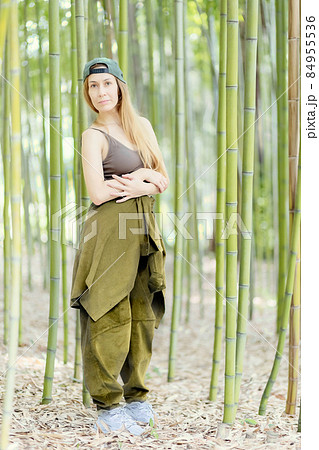 Hip-hop girl stands with folded arms in a green bamboo grove Hip-hop girl stands with folded arms in a green bamboo grove 84955536