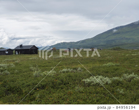 Lapland landscape at Virihaure lake with sami village Arasluokta houses, snow capped mountains and plain with shrubs. Sweden summer moody and foggy wild nature, Padjelantaleden hiking trail. 84956194