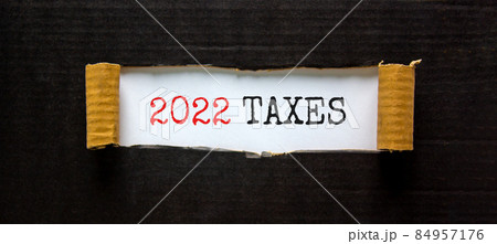 2022 taxes new year symbol. Words '2022 taxes' appearing behind torn black paper. Beautiful black background. Business, 2022 taxes new year concept, copy space. 2022 taxes new year symbol. Words '2022 taxes' appearing behind torn black paper. Beautiful black background. Business, 2022 taxes new year concept, copy space. 84957176