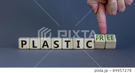 Plastic free and green business symbol. Businessman turns cubes, changes words 'plastic' to 'plastic free'. Beautiful grey background. Green business, ecological and plastic free concept. Copy space. 84957278