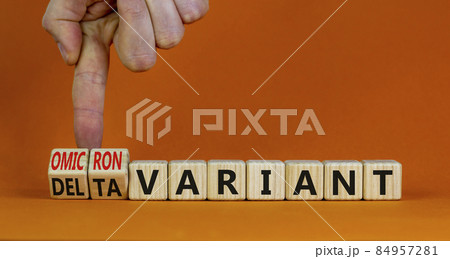 Covid-19 omicron variant symbol. Doctor turns cubes and changes words delta variant to omicron variant. Beautiful orange background. Medical, covid-19 and delta or omicron variant concept. Copy space. 84957281