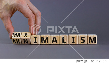 Minimalism or maximalism symbol. Businessman turns wooden cubes and changes the word minimalism to maximalism. Beautiful grey background. Business, minimalism or maximalism concept. Copy space. 84957282