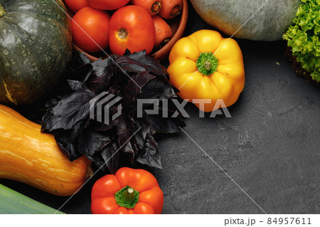 Assortment of vegetables including pumpkin, tomatoes and peppers on black background Assortment of vegetables including pumpkin, tomatoes and peppers on black background 84957611