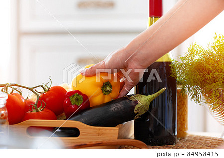 Female hand holding bell pepper above table Female hand holding bell pepper above table 84958415